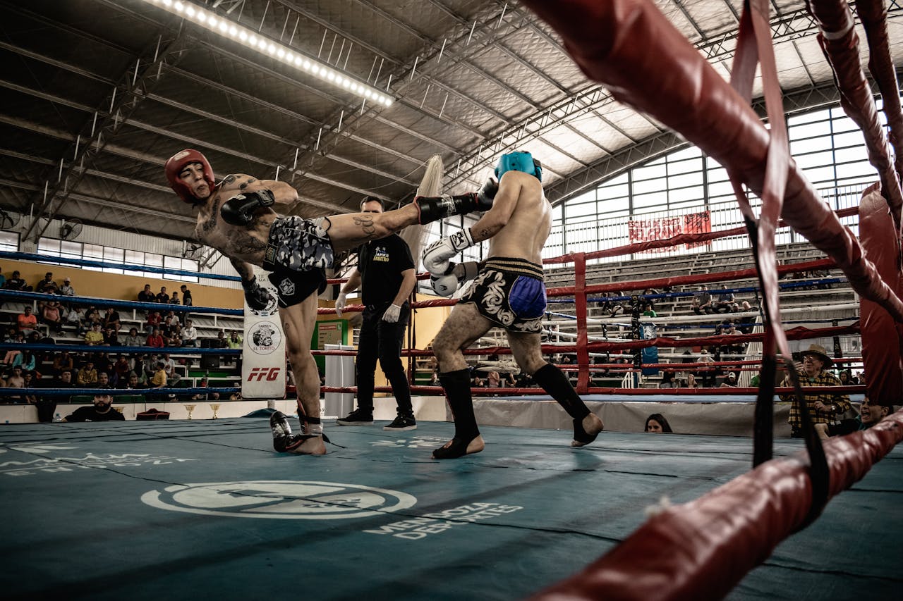 Intense action shot of a kickboxing match inside a packed arena, showcasing athleticism and skill.