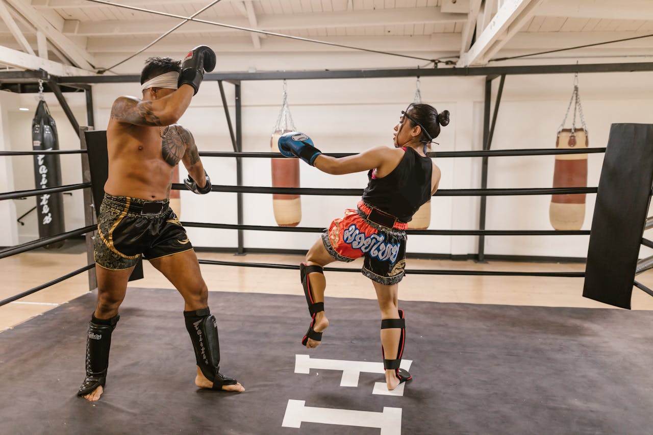 contact-img Two athletes engage in a dynamic Muay Thai sparring session inside a gym boxing ring.