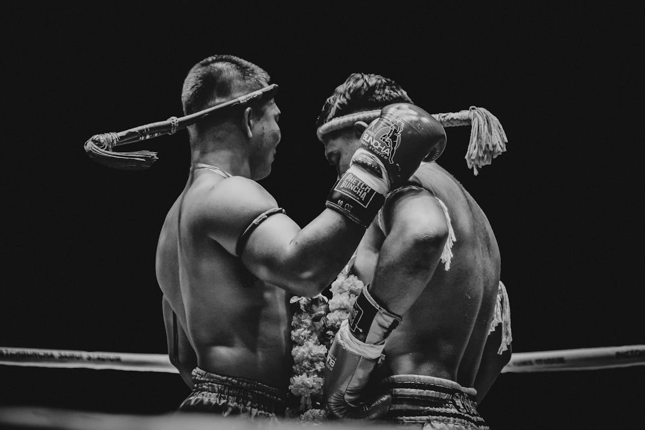 Black and white photo of two Muay Thai fighters in a ring, showcasing the intensity of the sport.